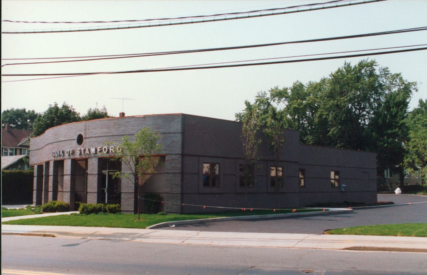 Gray, modern office building with curved facade and large windows; street and trees in the background.