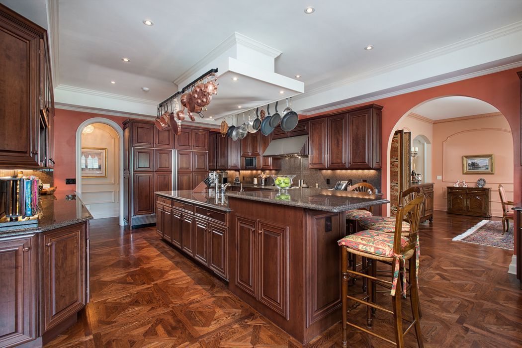 Kitchen with dark wood cabinets, island, and copper pots hanging above a stove.