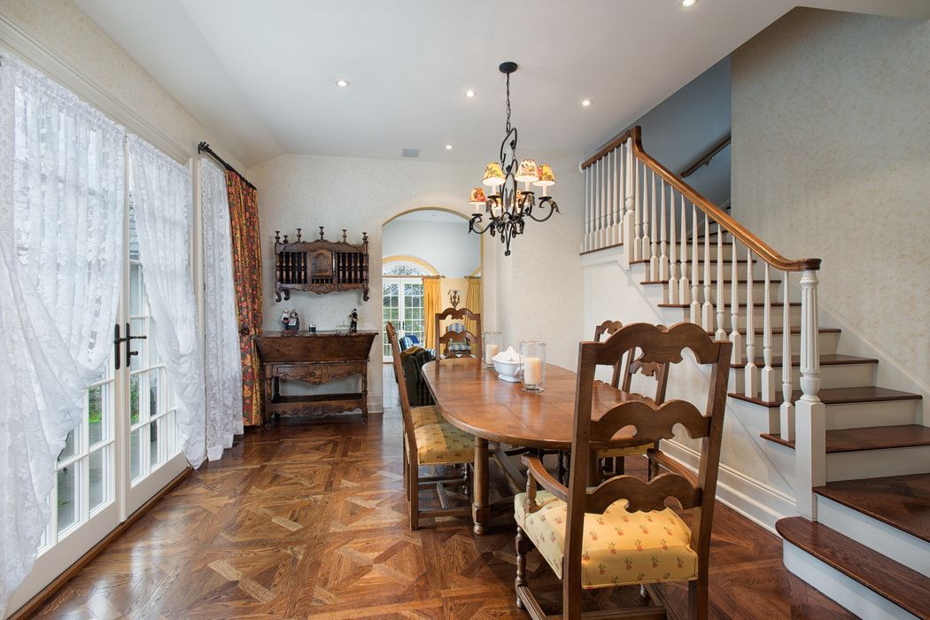 Formal dining room with wood flooring, table, chairs, and a chandelier. French doors and staircase.