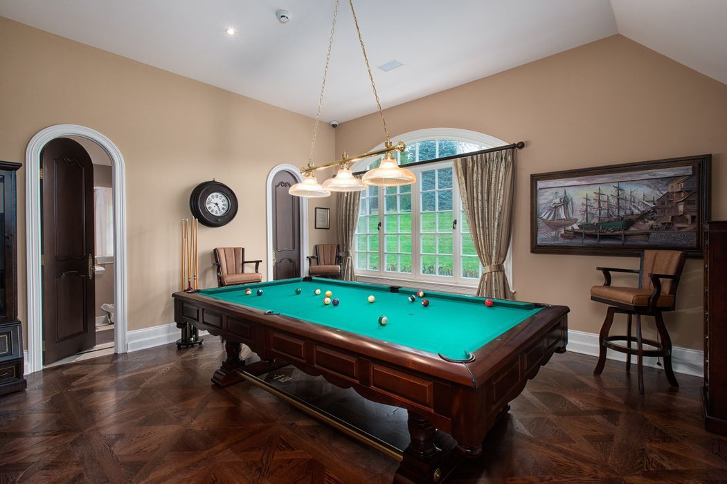 Pool table in a room with a window, artwork, and pendant lighting.