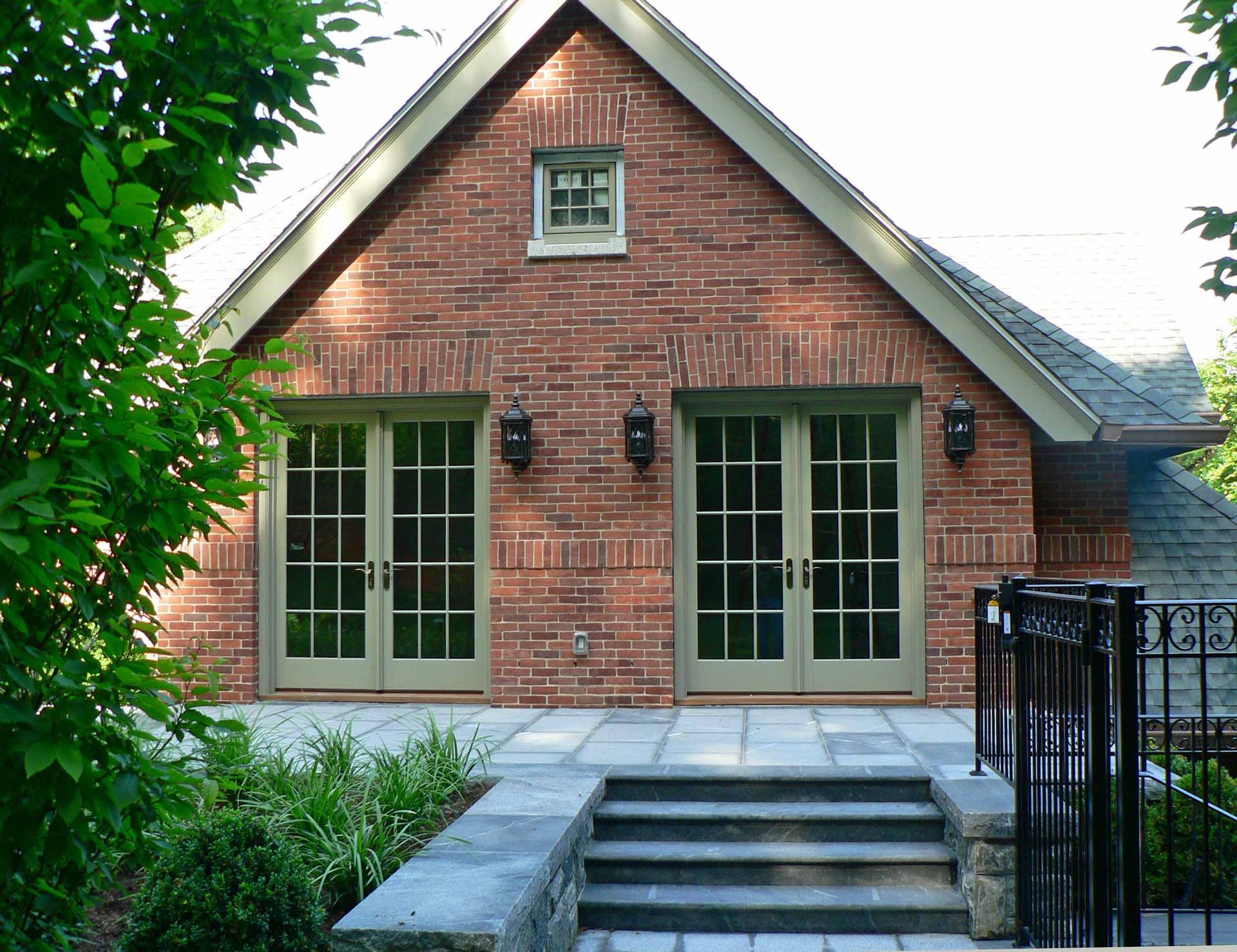 Brick building with two French doors, small window, and stone patio with steps.