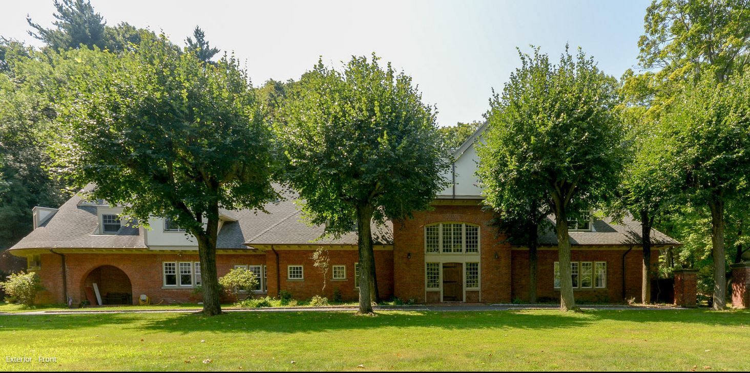 Brick building with trees in front, on a green lawn.