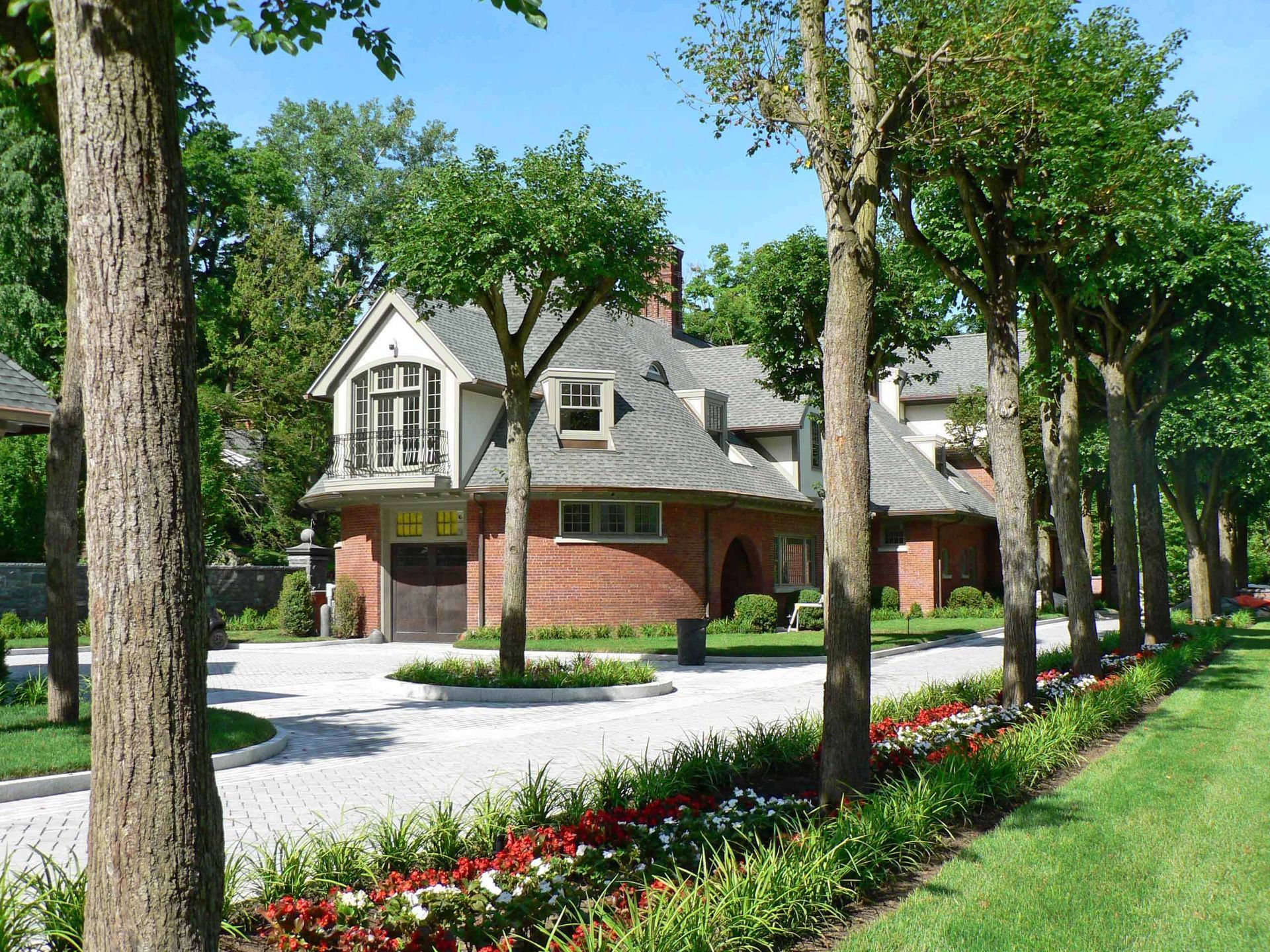 Brick home with a tree-lined driveway and flower bed.