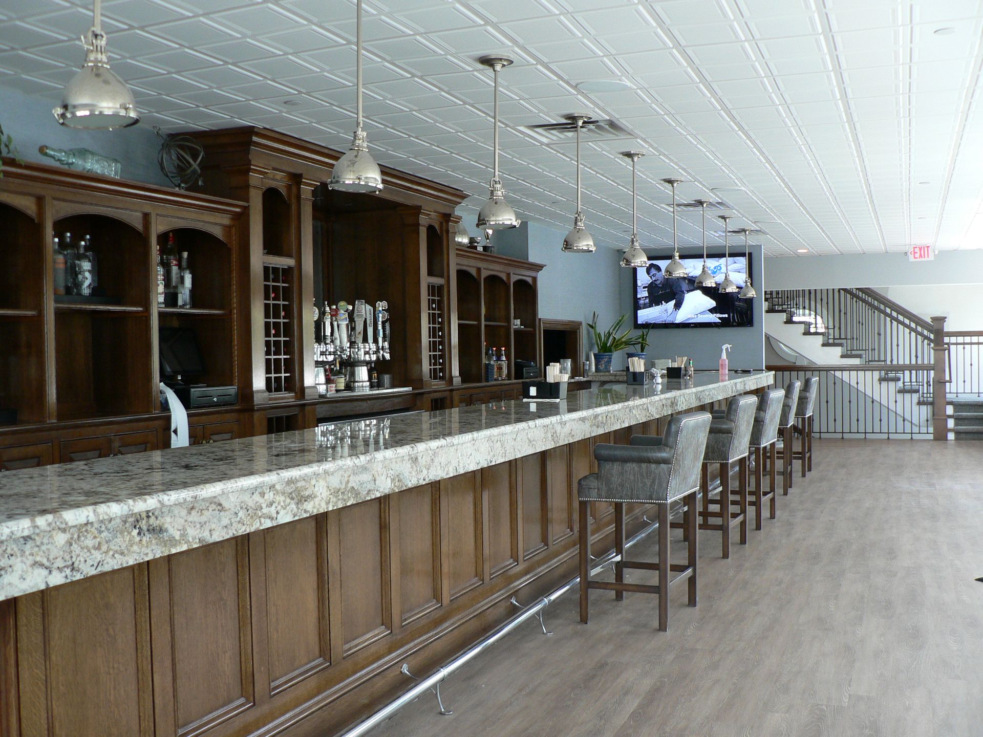 Bar interior with a wooden bar, stools, and a television.