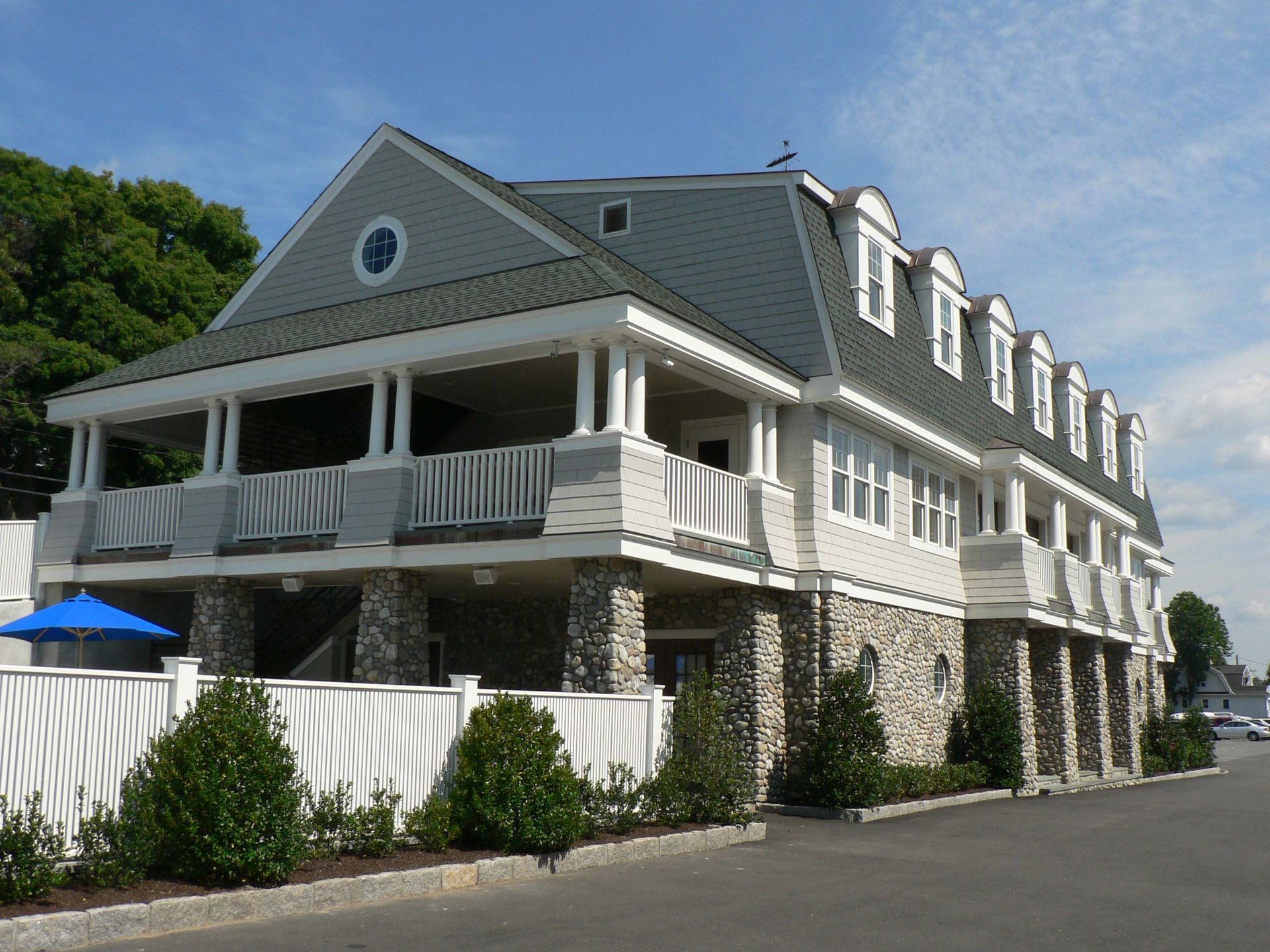 Three-story building with stone base, white siding, and a covered balcony.