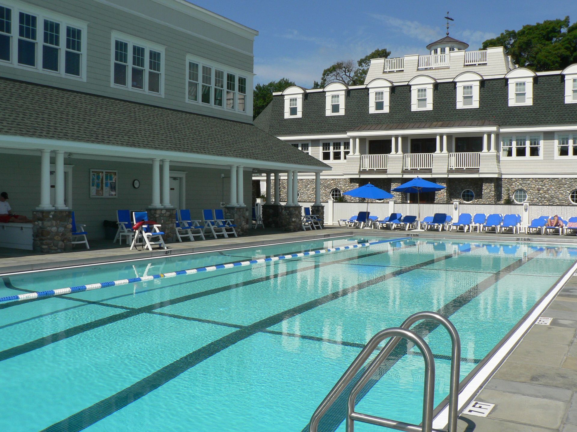 Swimming pool with blue lounge chairs, buildings in background.