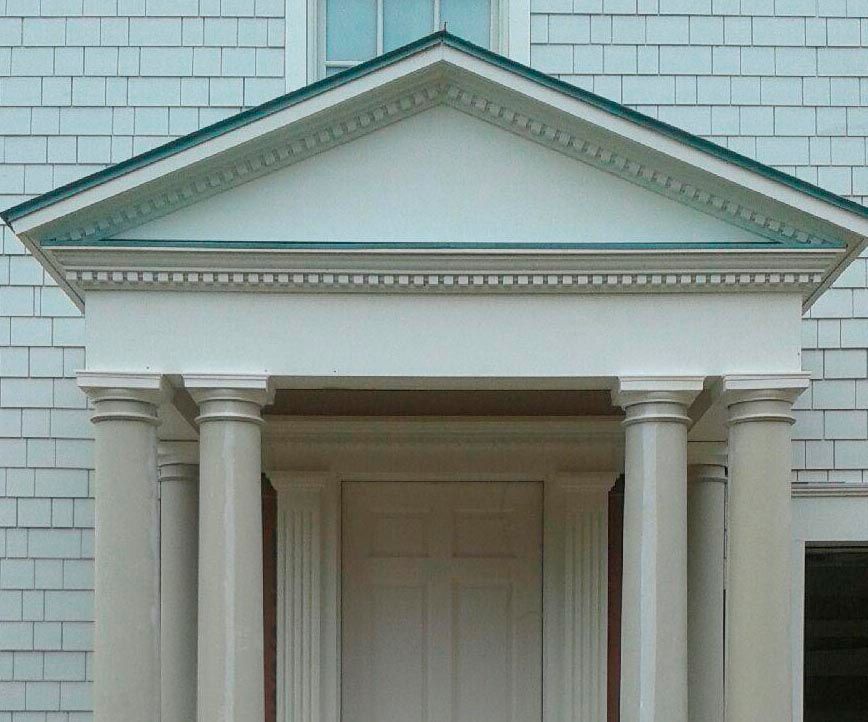 White entranceway with columns and triangular pediment. Green trim accents the design.