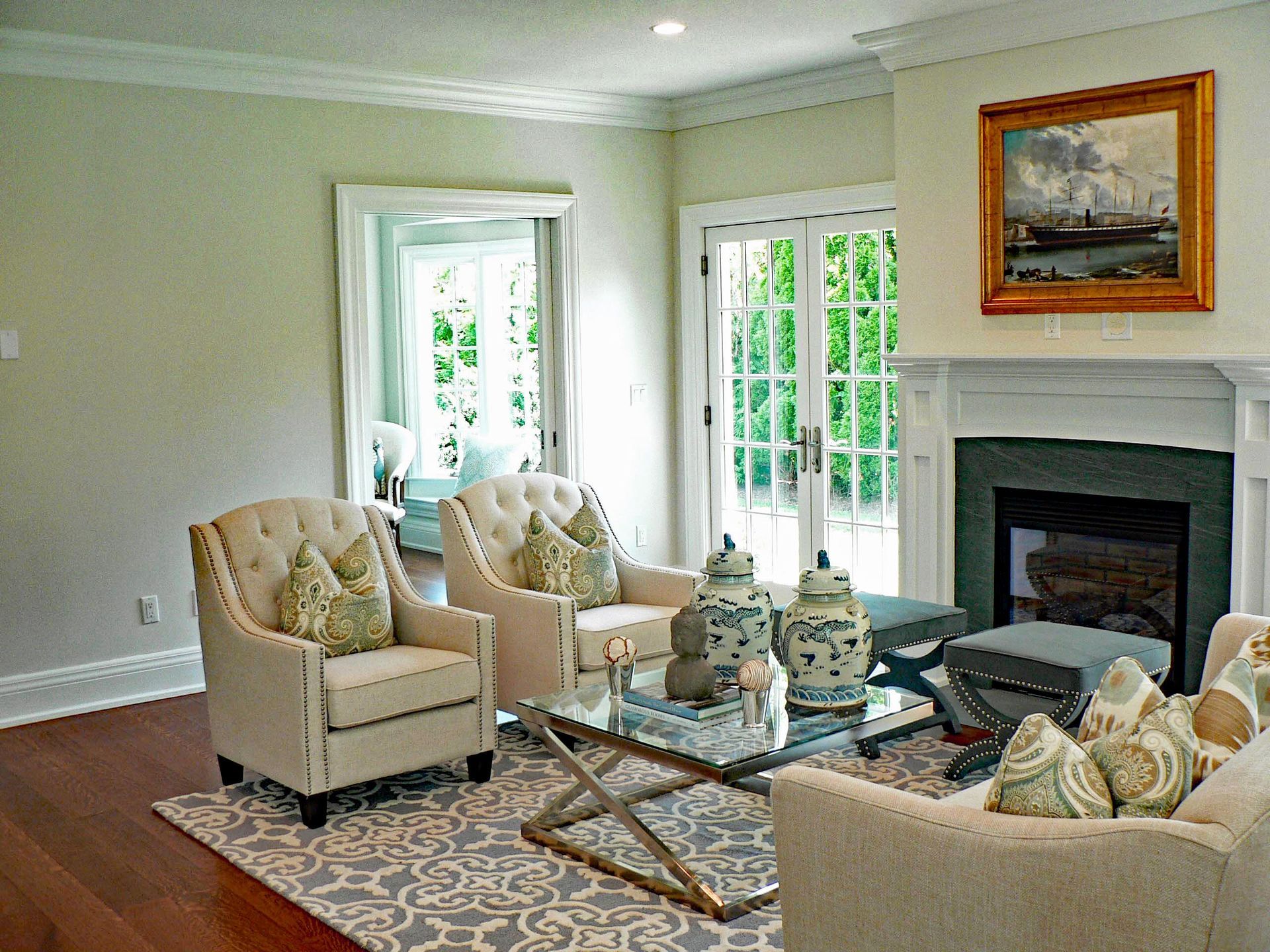 Living room with upholstered furniture, fireplace, and French doors leading outside.