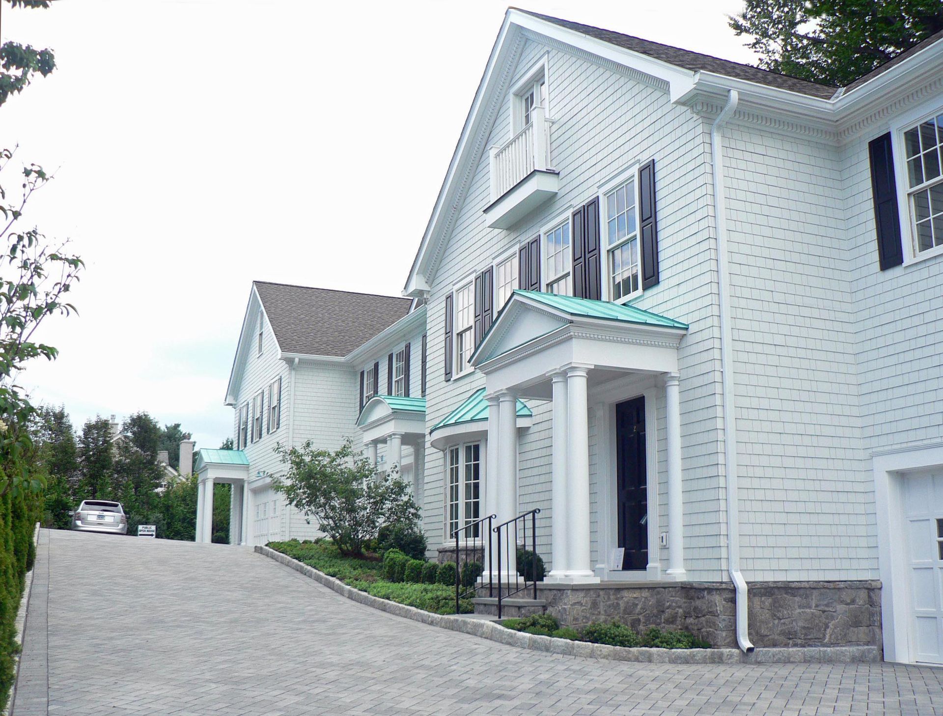 White house with brick driveway and black shutters.