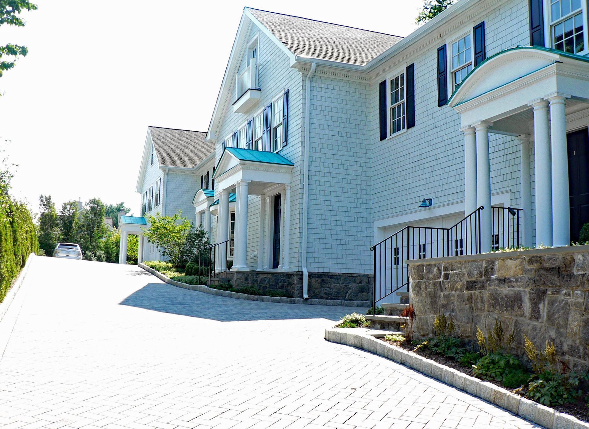 White house with blue accents and brick driveway.
