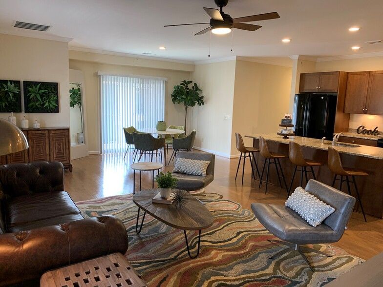 Open-concept living space with kitchen, dining area, and living room; hardwood floors, neutral walls, modern decor.