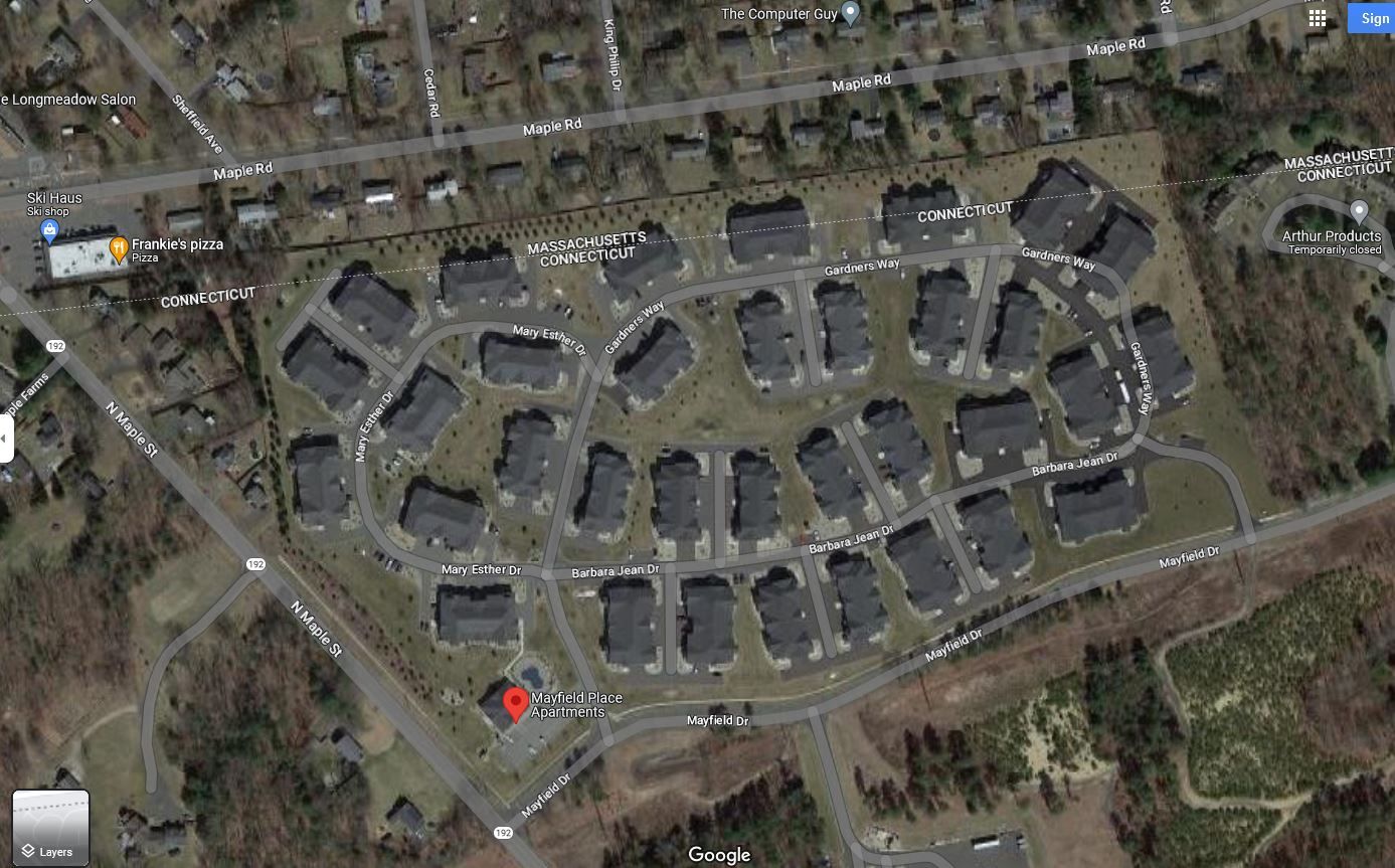Aerial view of a residential neighborhood with dark-roofed houses arranged in a curved pattern on a green lawn.