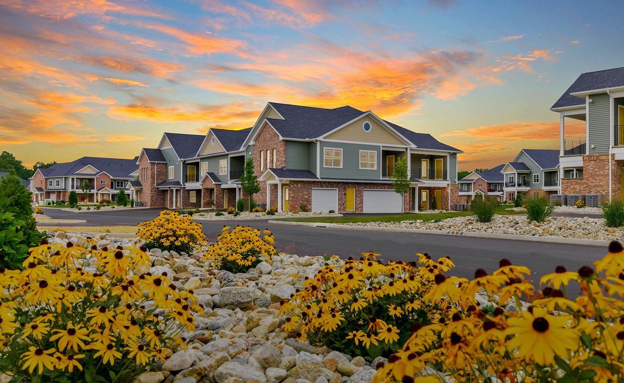 Apartment complex with colorful sunset, yellow flowers, and stone landscaping.