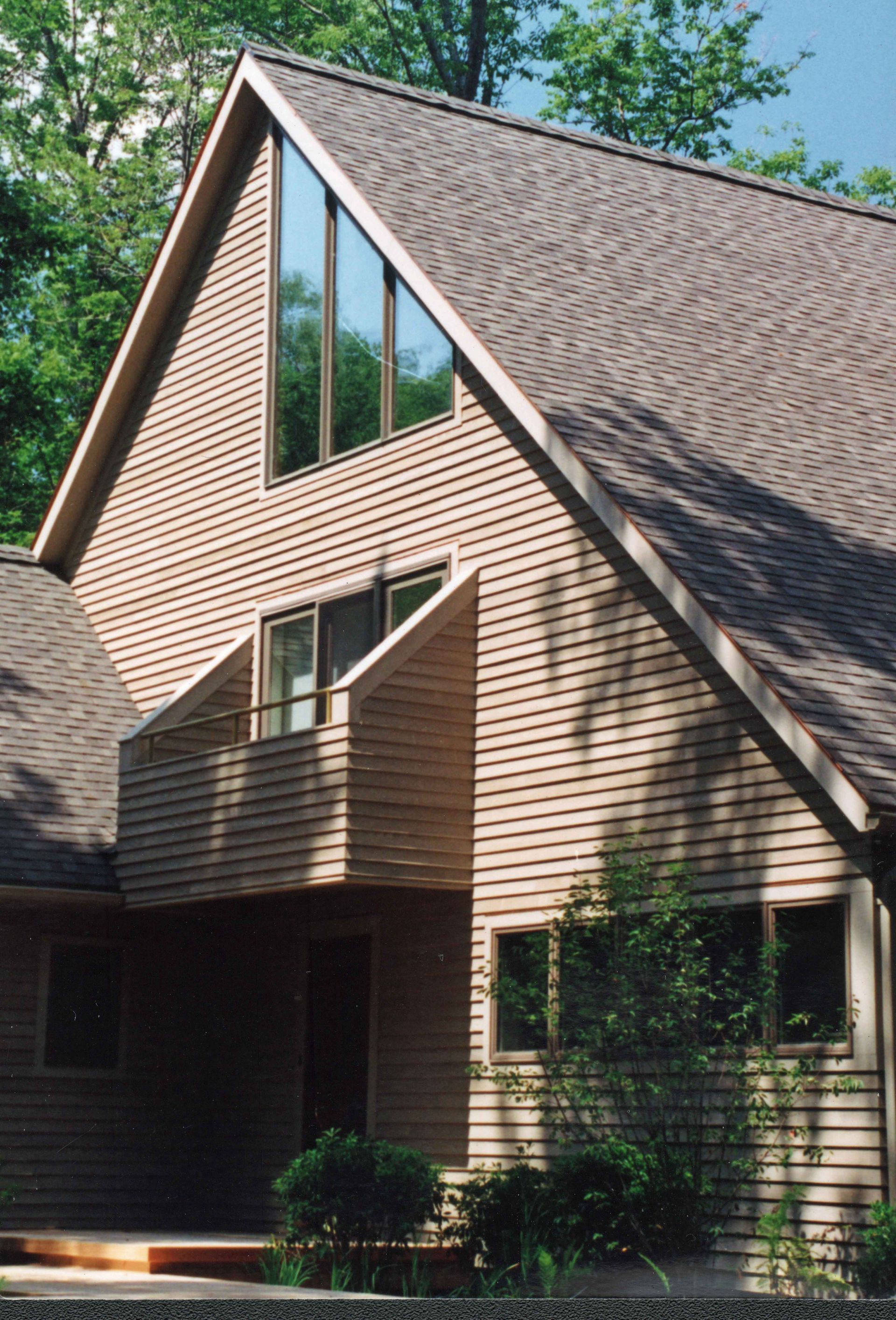 Tan house with large triangle window and angled roof.