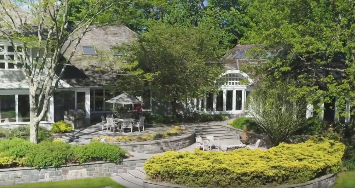 Stone home with a thatched roof and outdoor dining area surrounded by lush greenery.