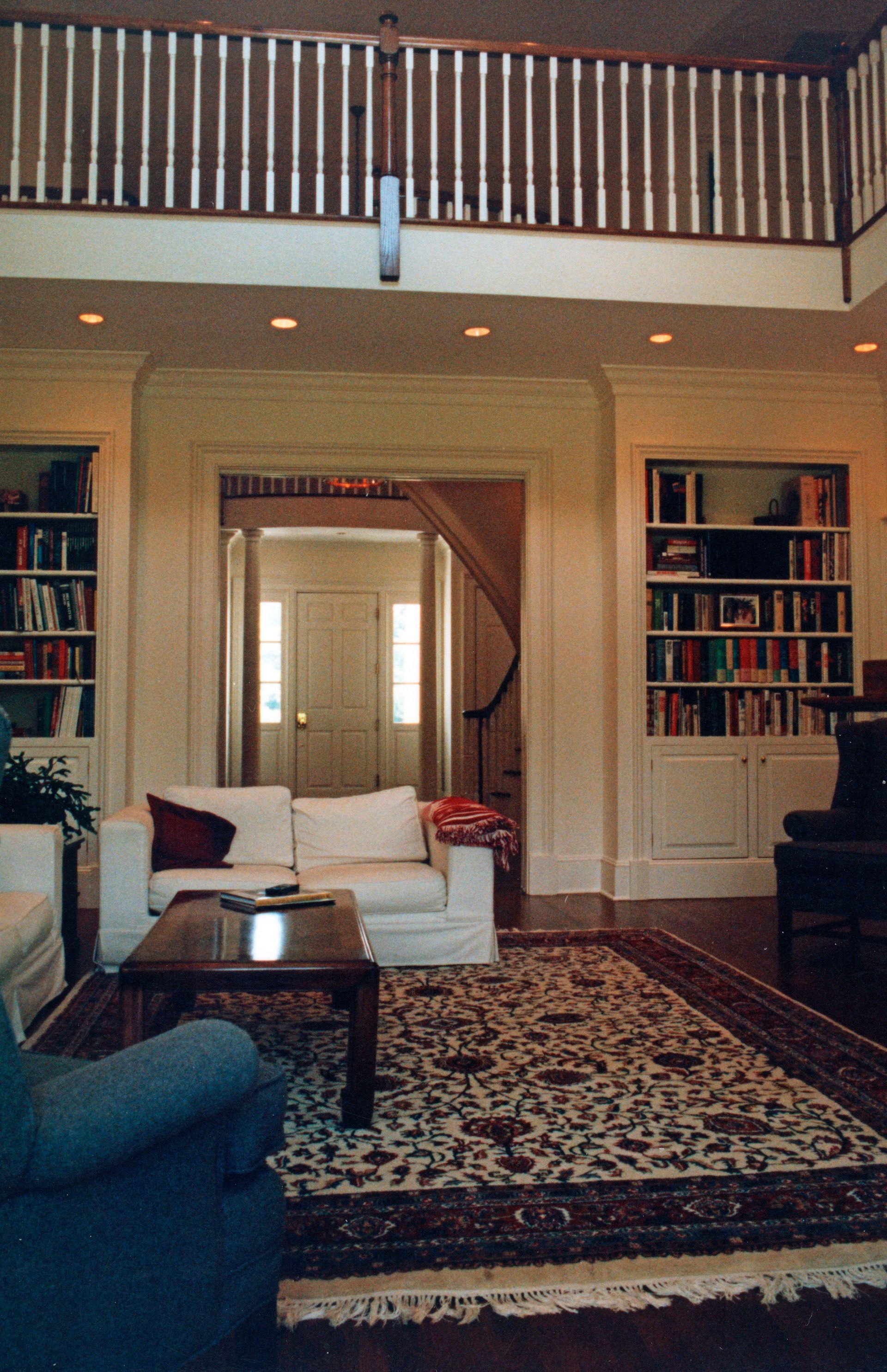 Living room with built-in bookshelves, sofa, area rug, doorway, and balcony railing.