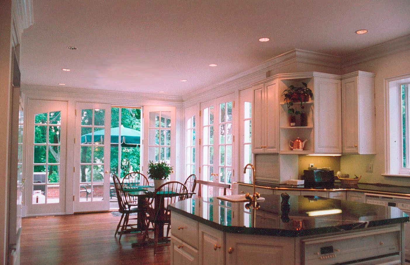Bright kitchen with white cabinets, dark island, and glass doors leading to a patio.