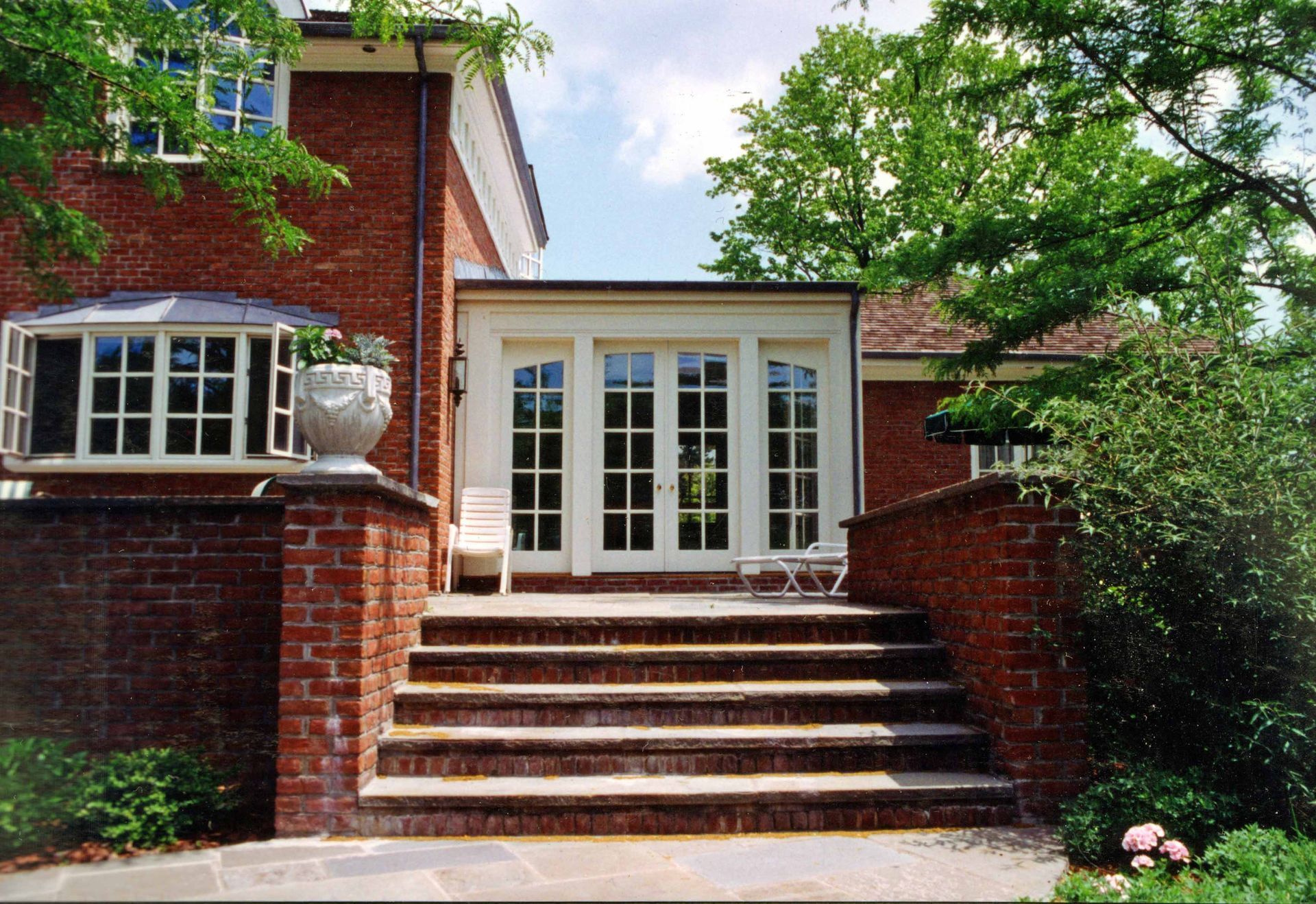 Red brick home with steps leading to a doorway with double doors. White trim and stone steps.