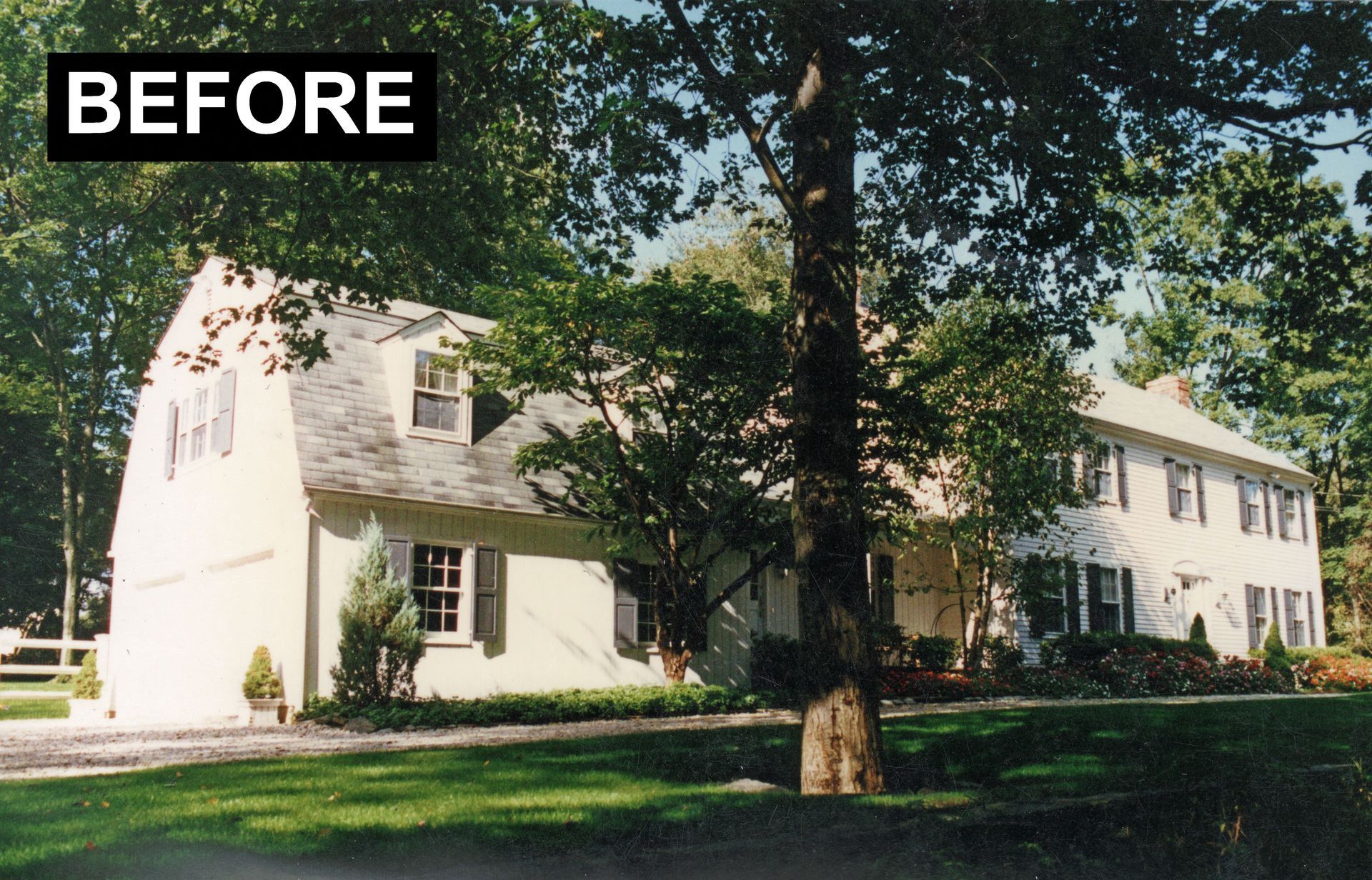 Beige house with a long, multi-section facade, surrounded by trees.