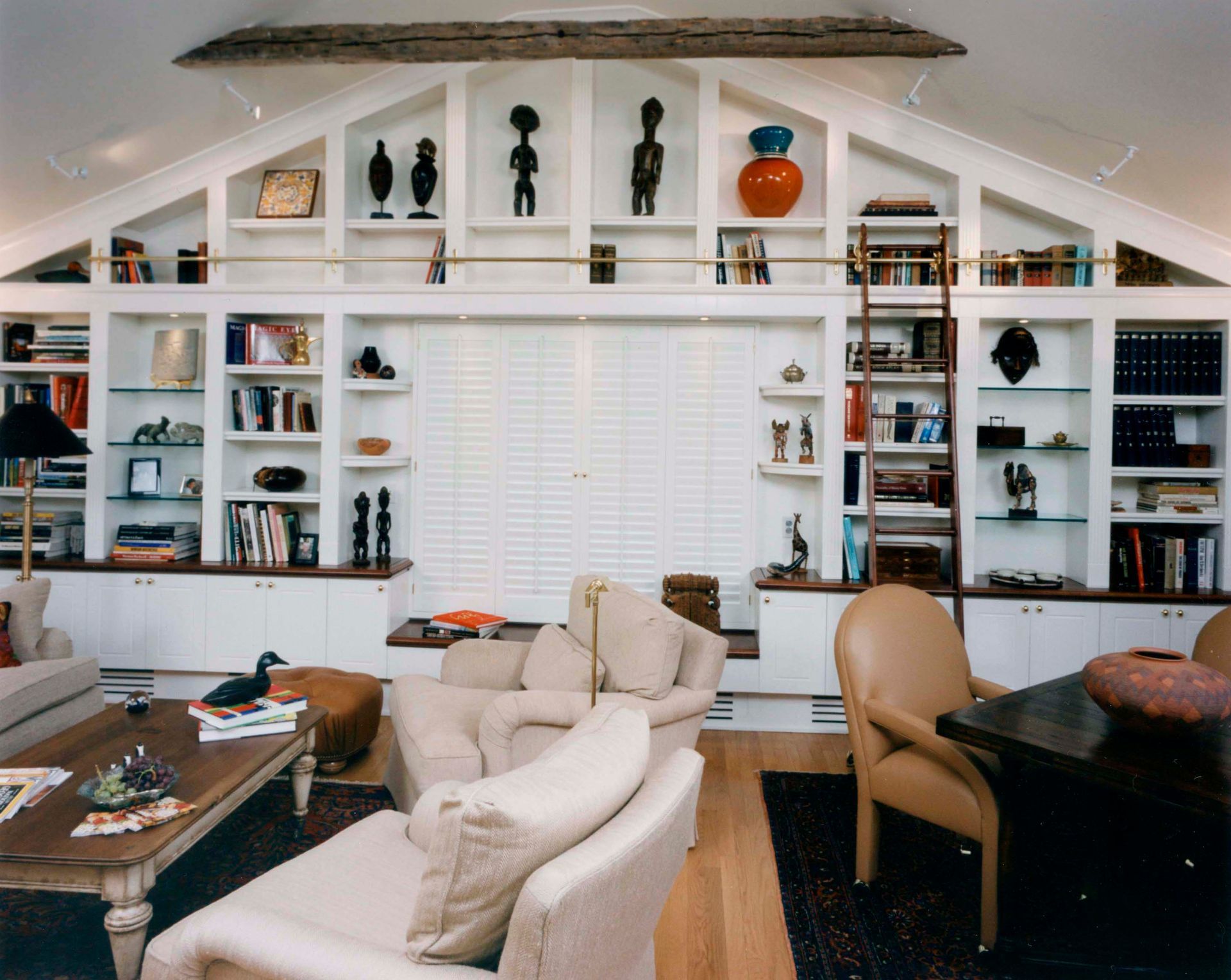 Living room with white built-in bookshelves, various decor, seating, and a window.