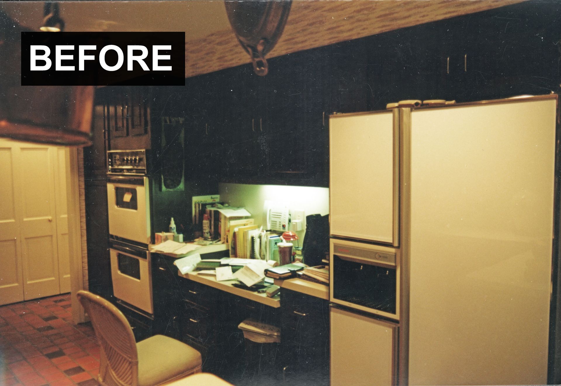 Dark kitchen with appliances, cabinets, and a messy countertop.