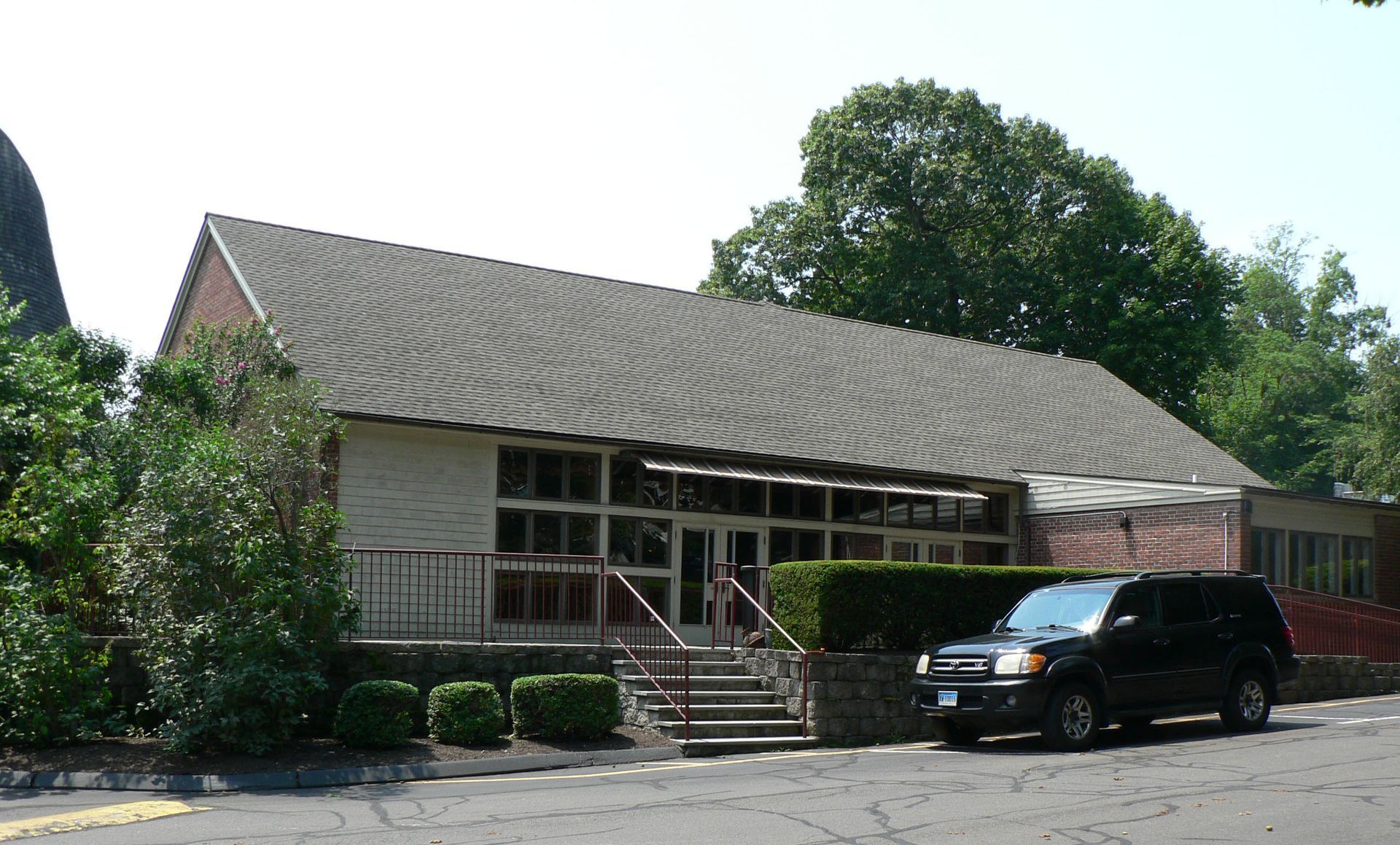 A one-story building with a curved roof. A black SUV is parked in front.