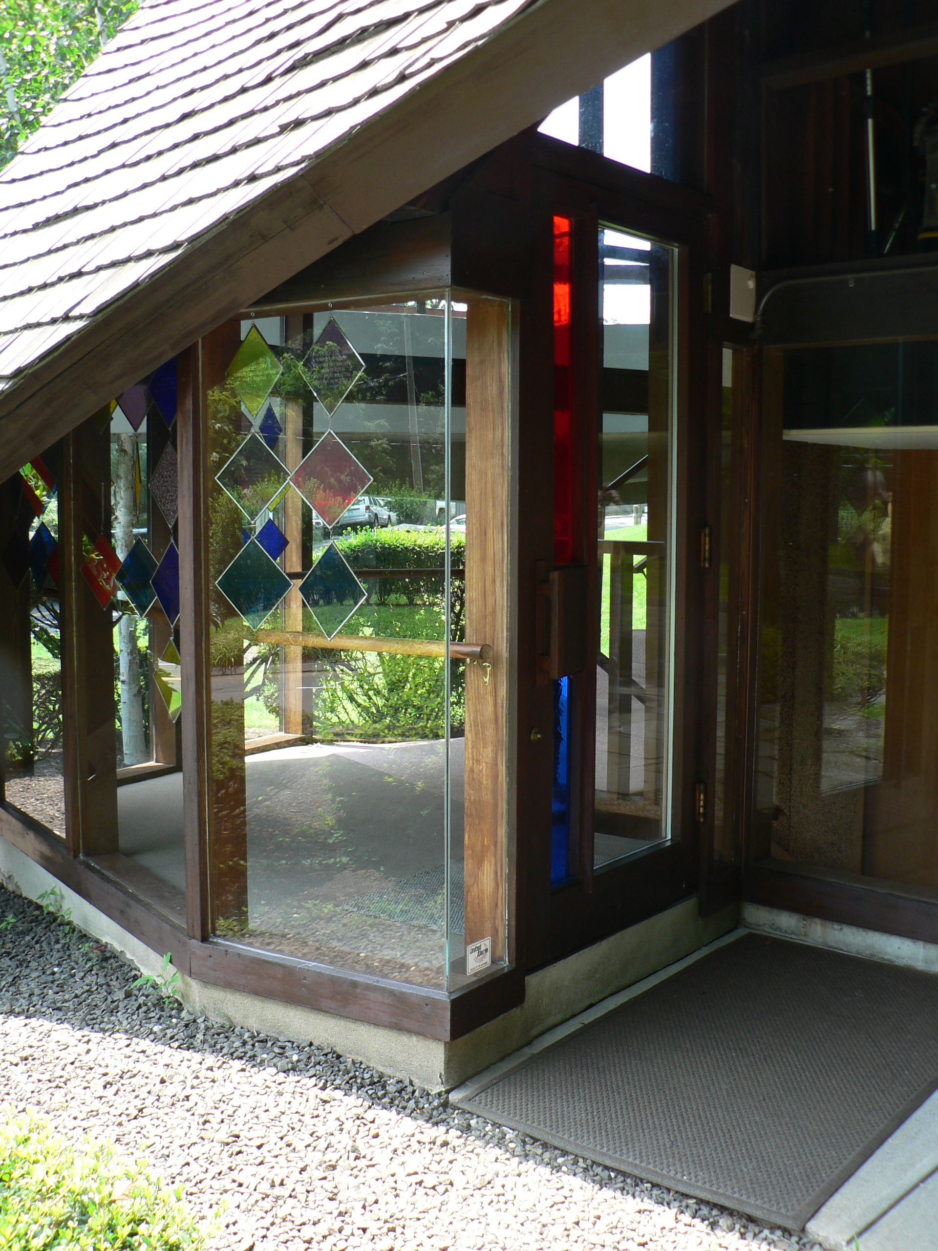 Entrance to building with wooden frame, glass door, stained glass accents, and a welcome mat.