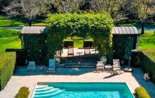 Outdoor pool with steps, lounge chairs, and ivy-covered archway.