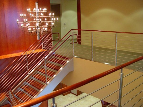 A Staircase with A Stainless Steel Railing and A Chandelier Above It
