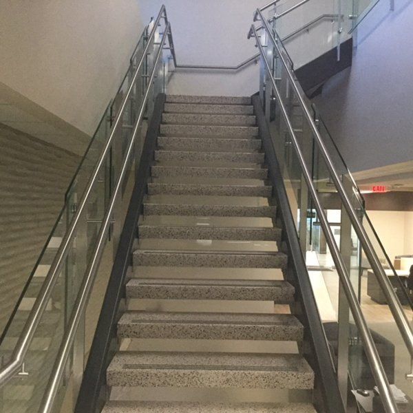 A Set of Stairs with A Glass Railing and A Red Exit Sign