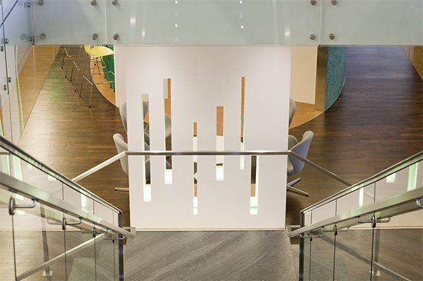 A Staircase with A Glass Railing and A White Wall