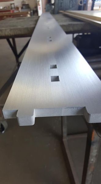 A Long Piece of Metal Is Sitting on Top of A Wooden Table