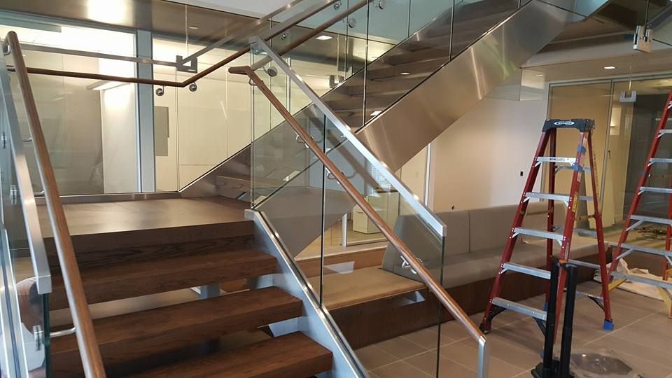 A Ladder Is Sitting Next to A Wooden Staircase with A Glass Railing