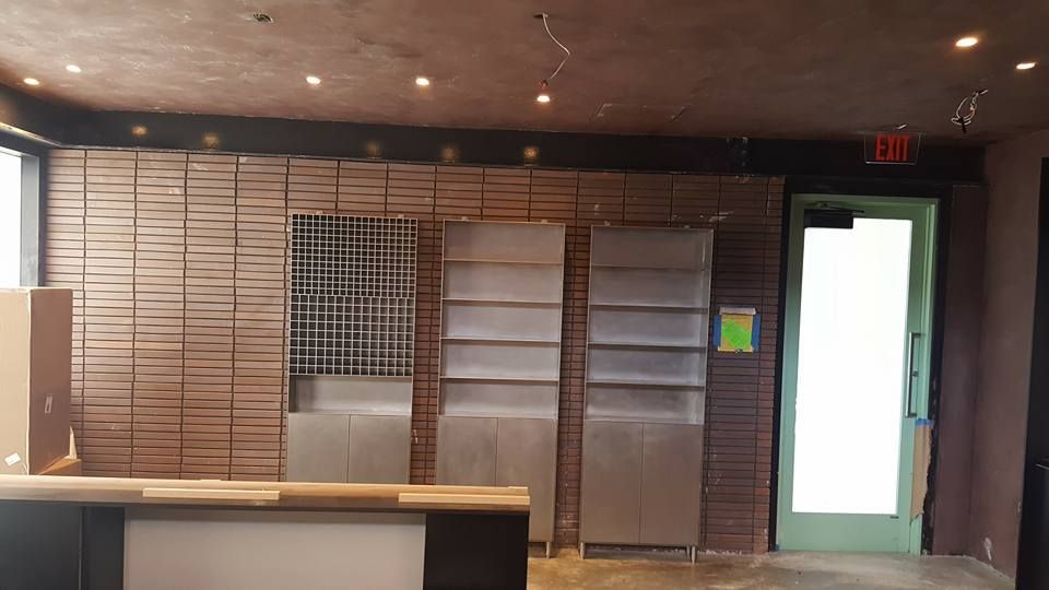 An Empty Room with A Green Door and A Brick Wall