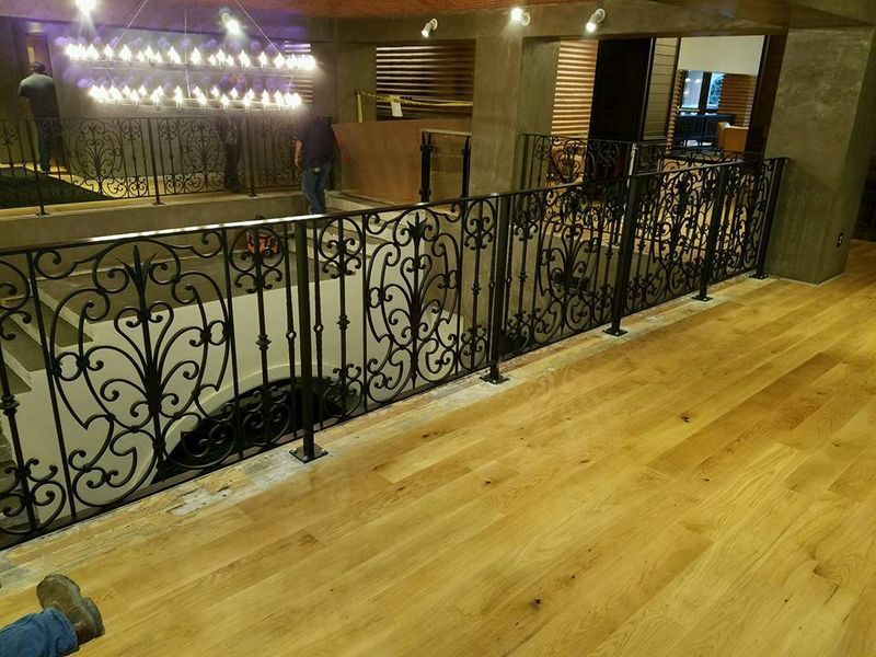 A Person Is Standing on A Wooden Floor Next to A Wrought Iron Railing