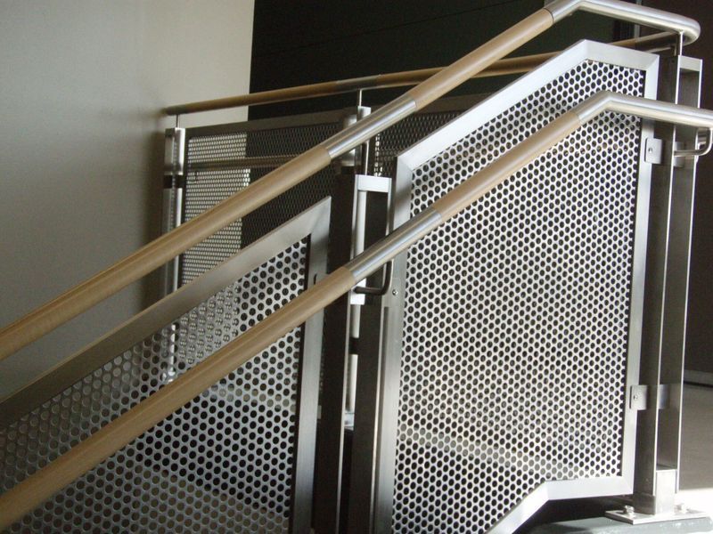 A Staircase with A Perforated Metal Railing and Wooden Handrails