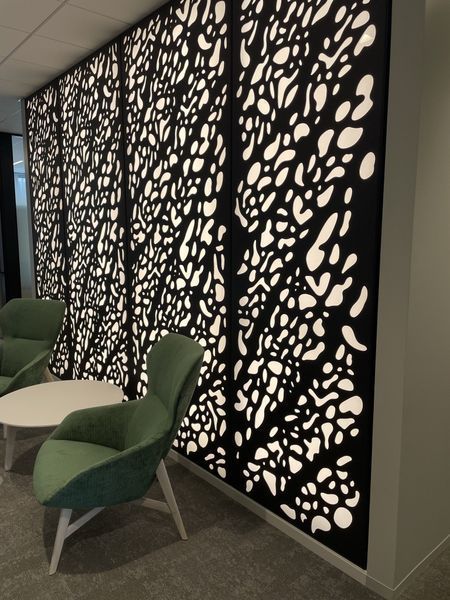 A Room with Chairs and A Table in Front of A Wall with A Pattern on It