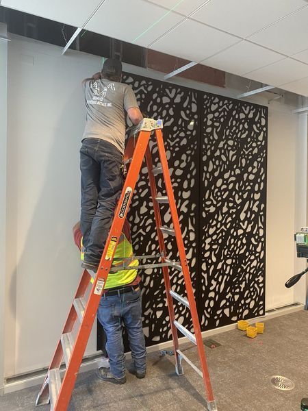 Two Men Are Standing on A Ladder Working on A Wall