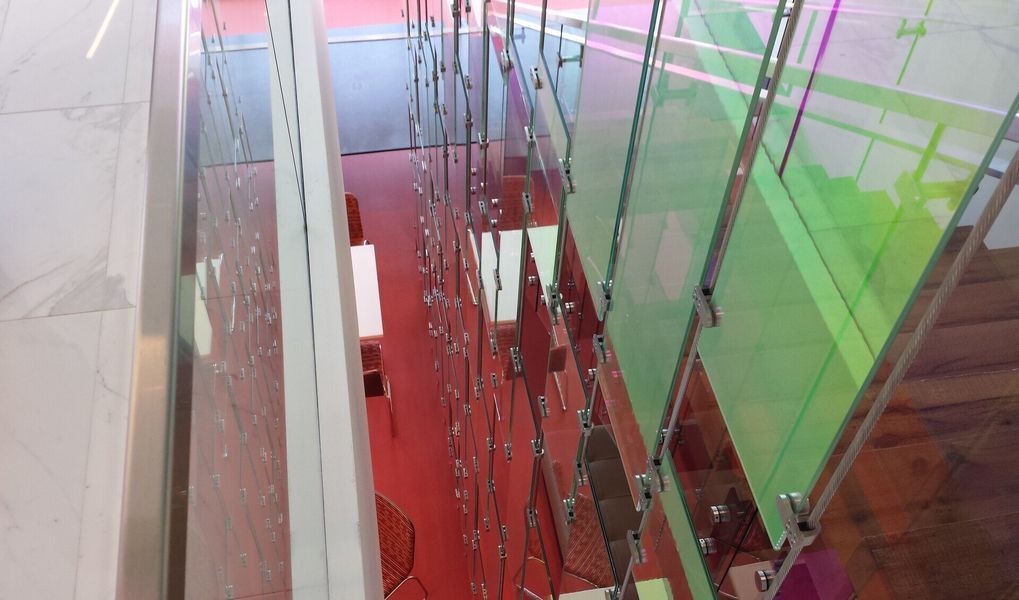 A Staircase with A Rainbow Colored Railing and A Red Floor