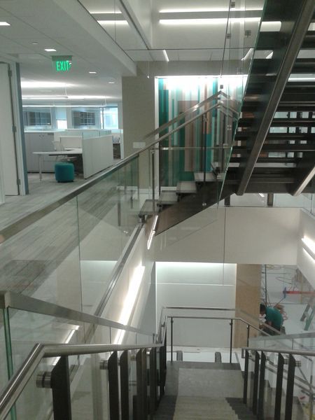A Staircase with A Glass Railing and A Green Exit Sign