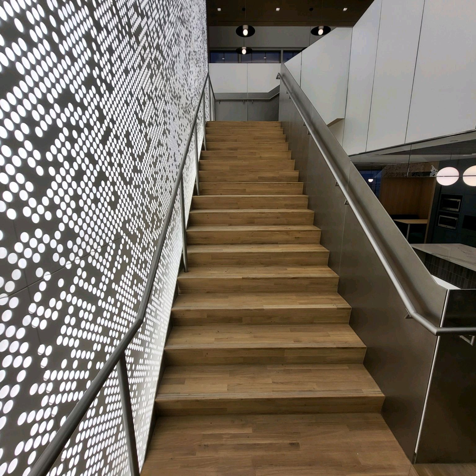 A set of wooden stairs with a stainless steel railing