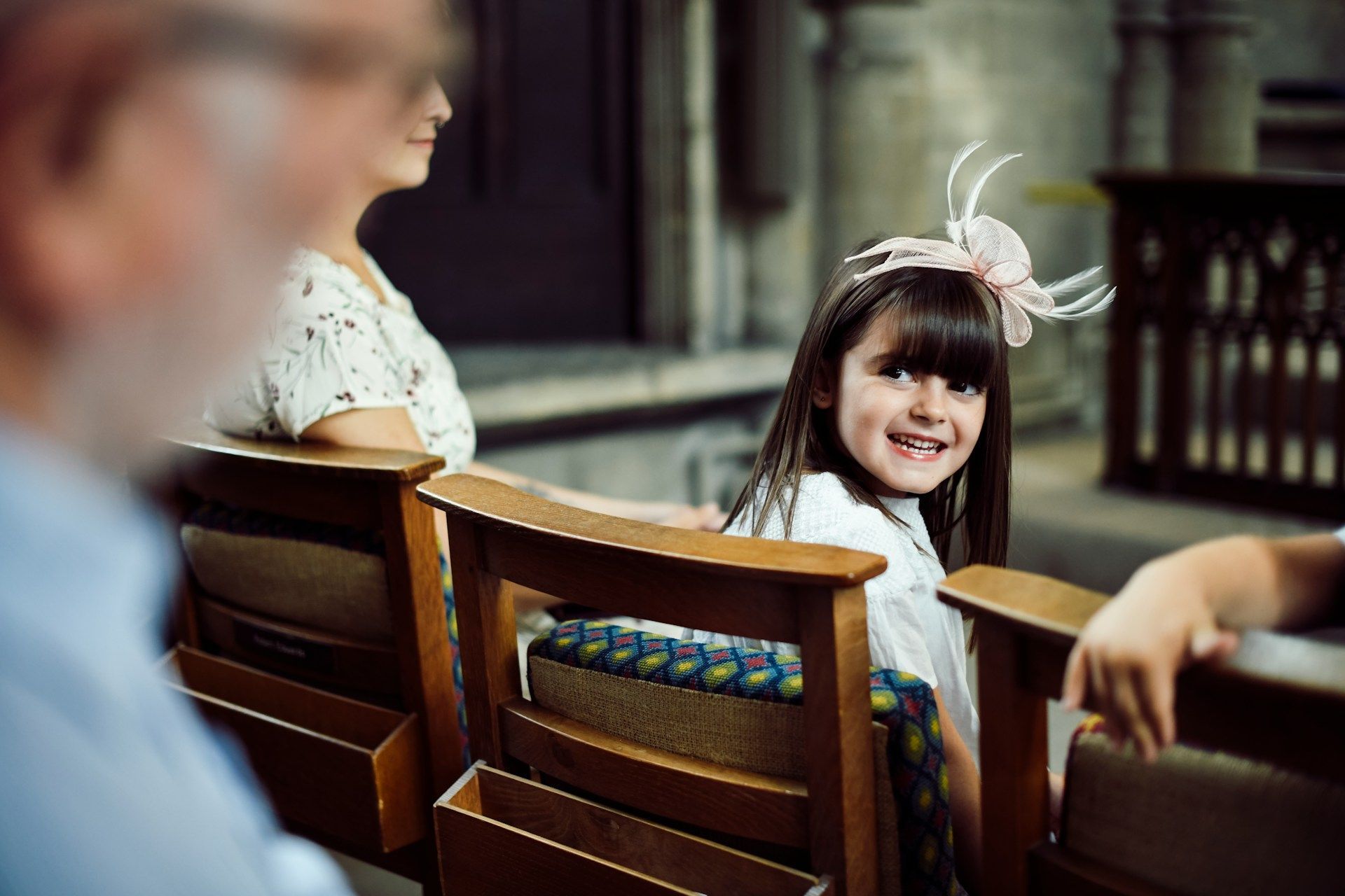 Green field with curved rows of young crops, trees in the background under a bright sky.