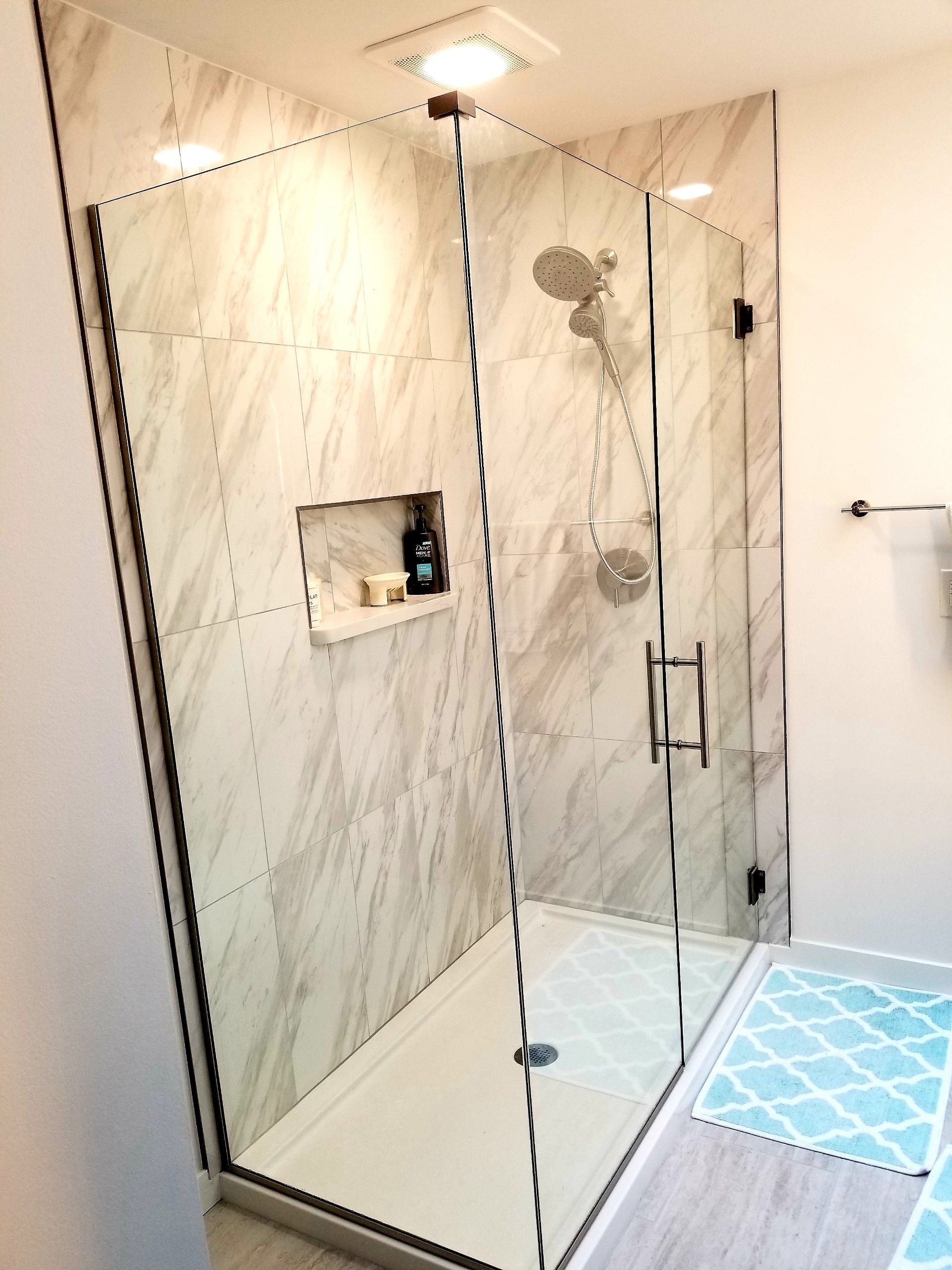 A bathroom with a walk in shower with a glass door