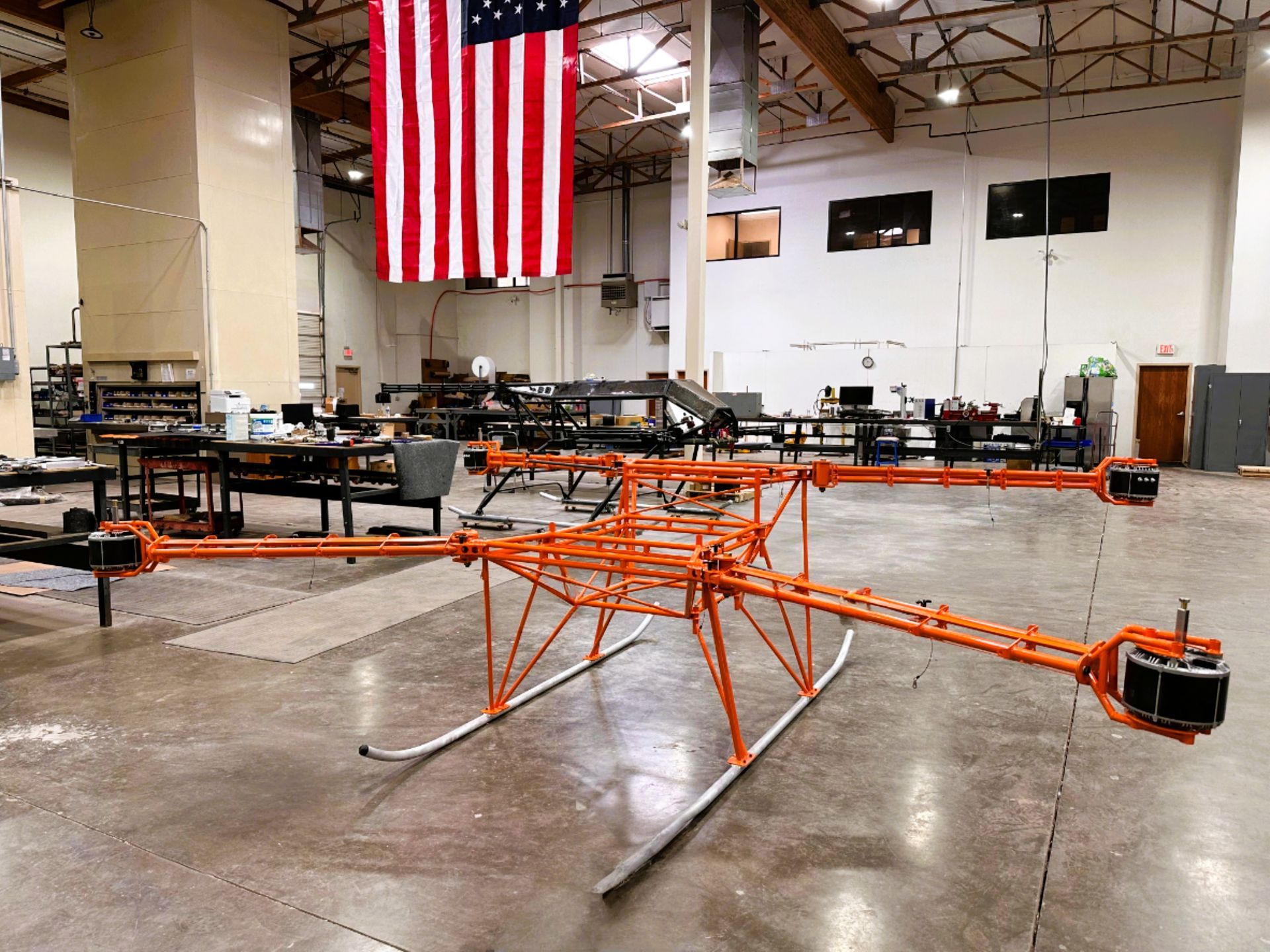 Large orange drone in a workshop; American flag in background.