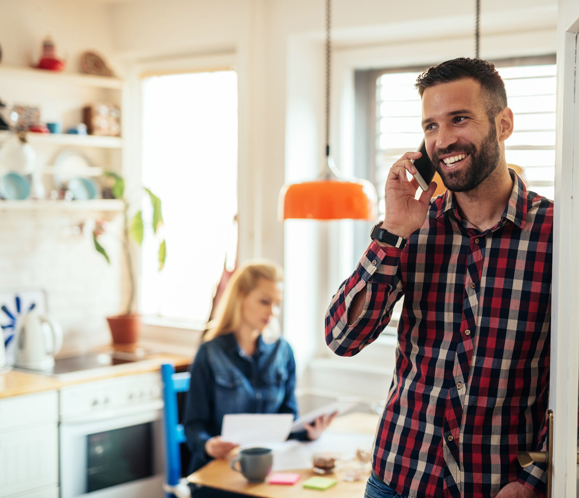 A man in a plaid shirt is talking on a cell phone