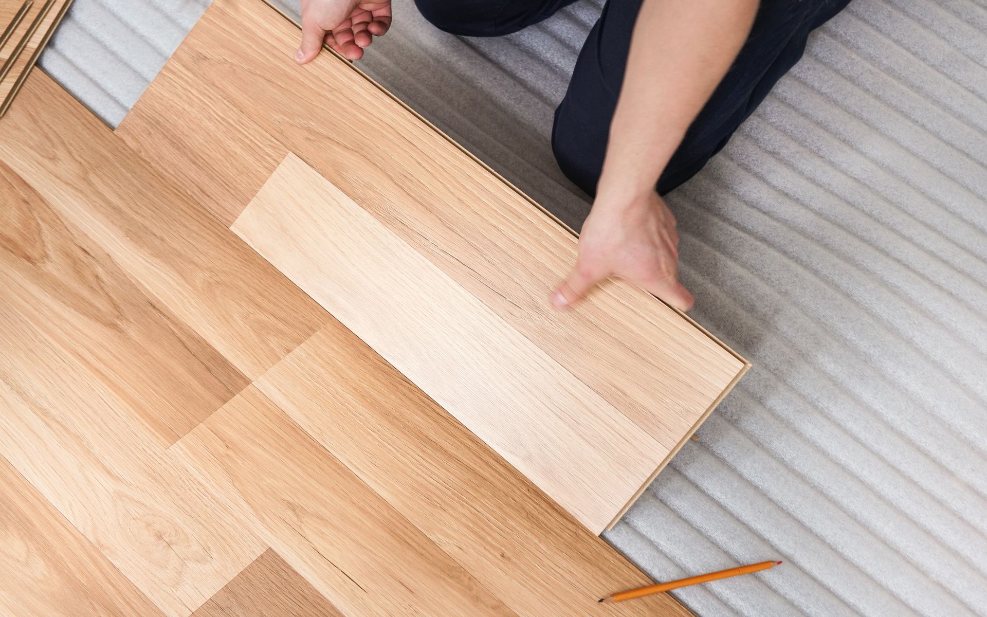 A person is installing a wooden floor in a room.