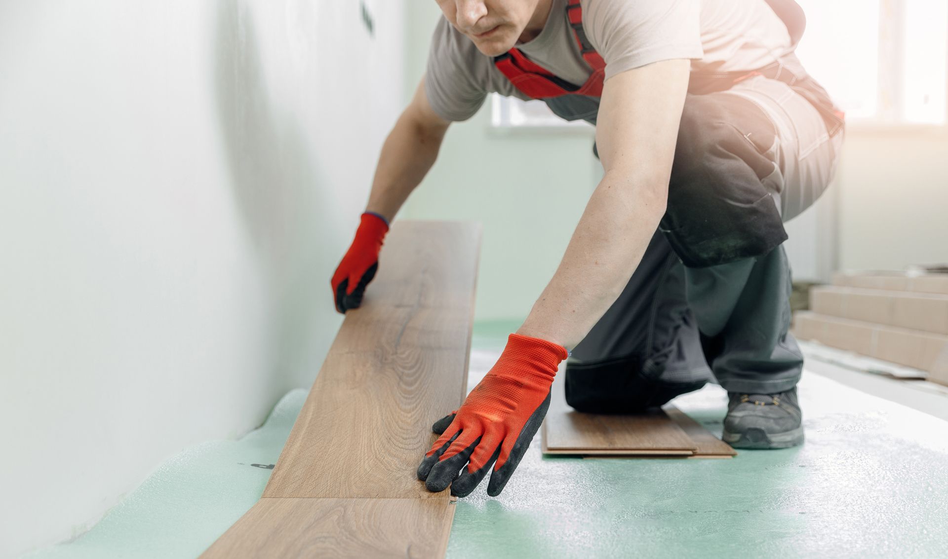 A man is installing a wooden floor in a room.