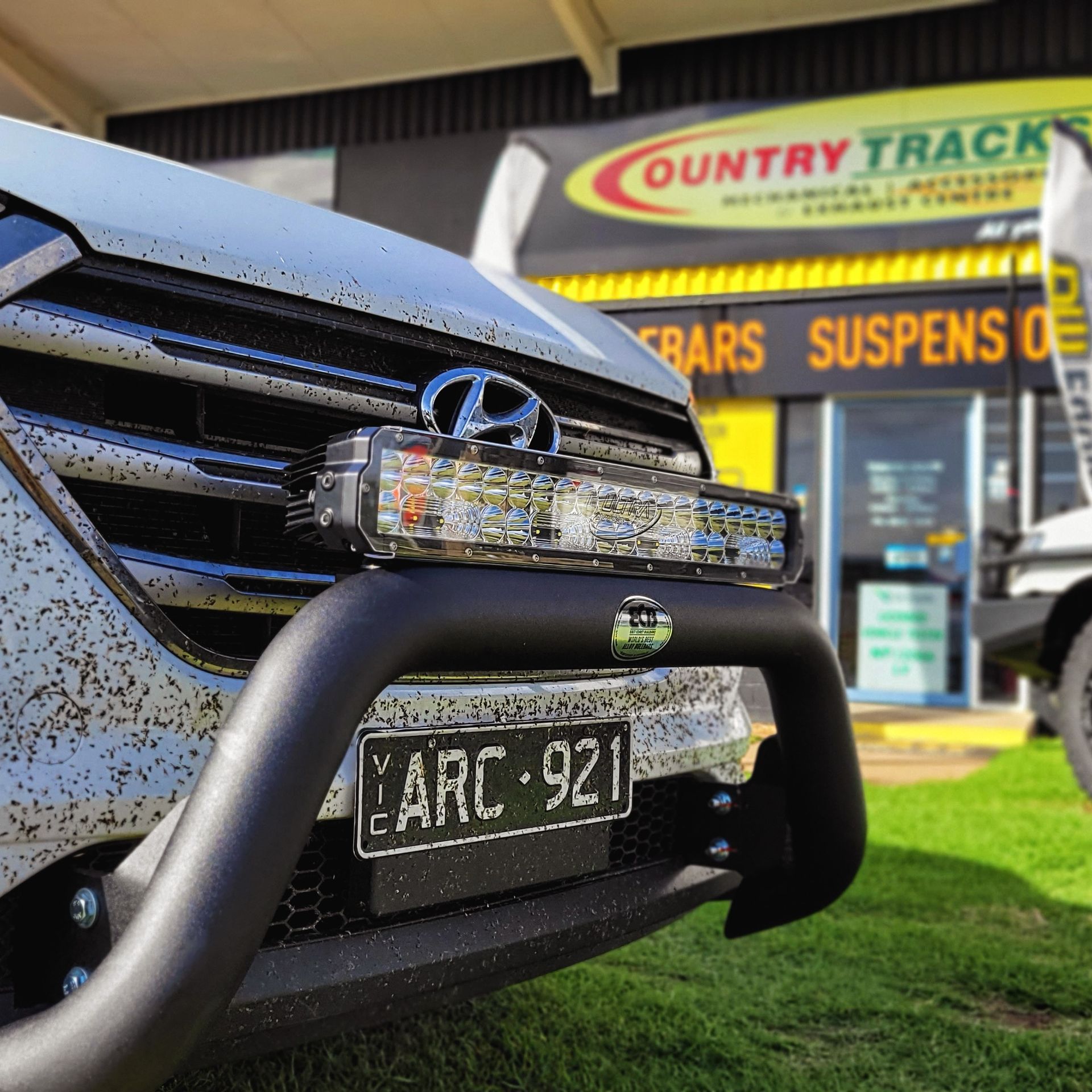 Black pickup truck with chrome bull bar parked next to a silver sedan.