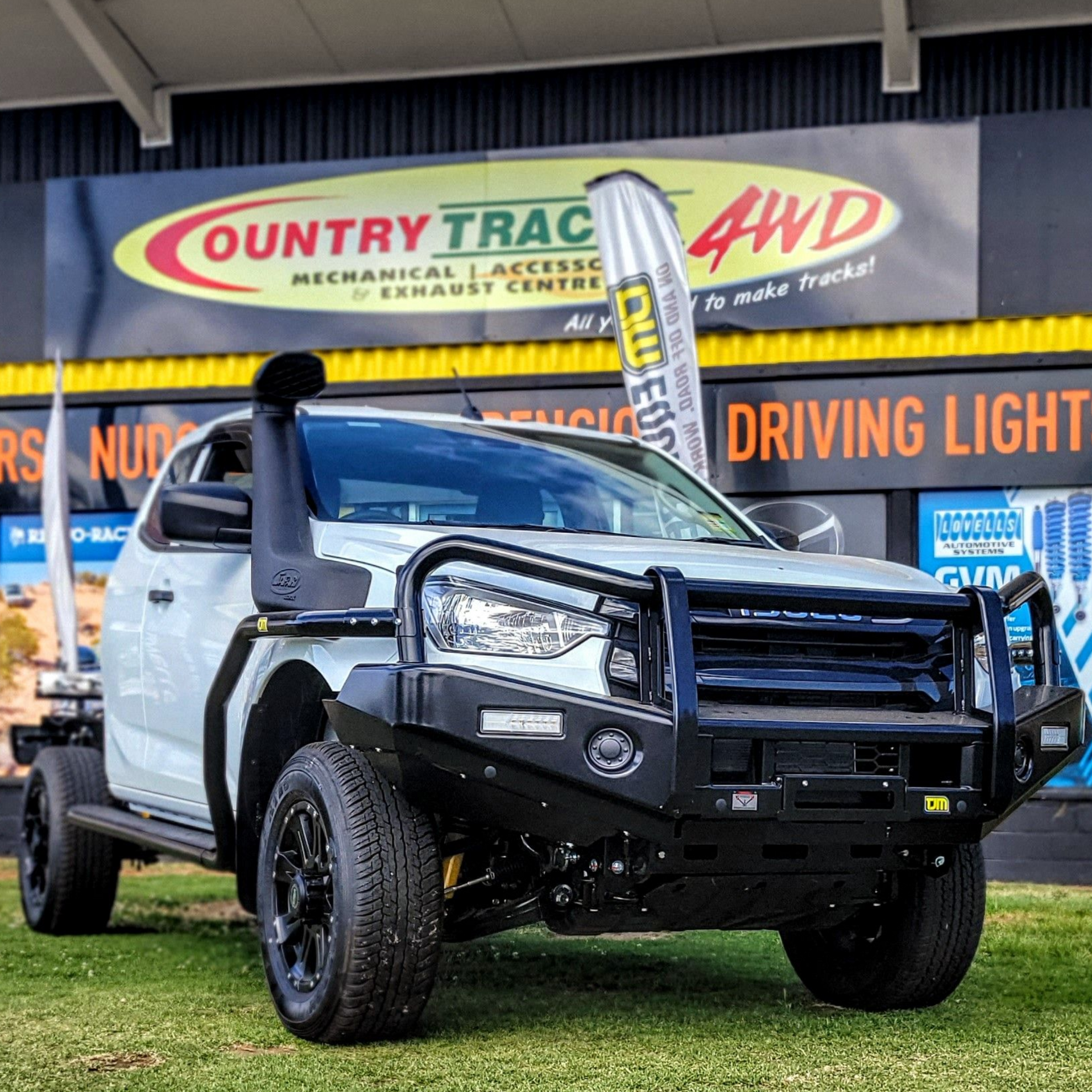 White pickup truck with black bull bar, spotlights, and winch, parked on grass.