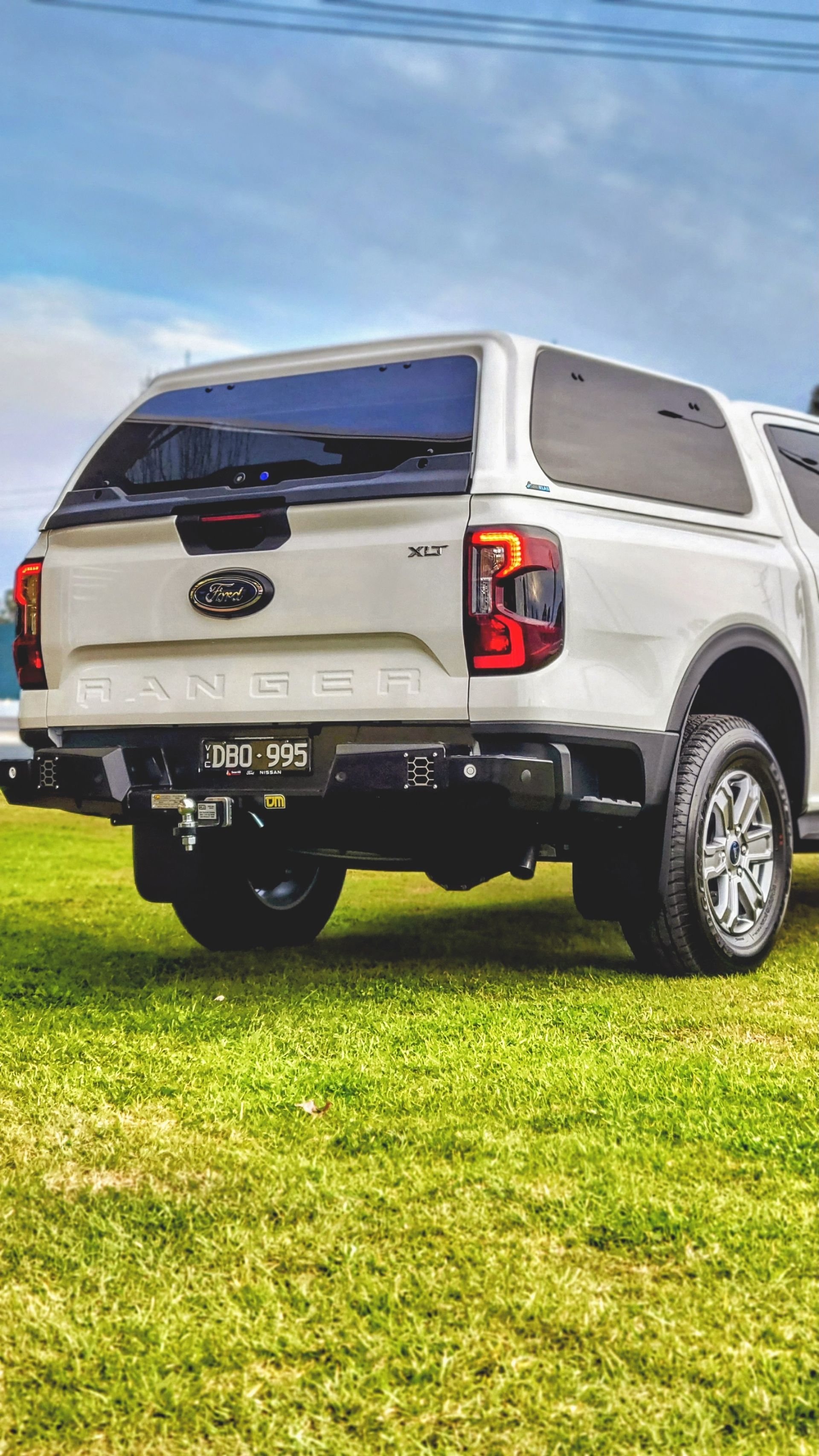 Silver and blue Toyota truck bumper with step, tow hitch, and red taillight.